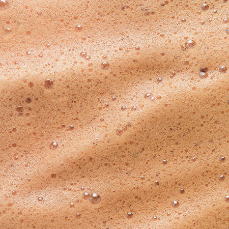 Close-up texture of Tropic Sun Drench overnight tanning mousse, the texture appears airy and bubbly, with a smooth and creamy consistency, indicative of its mousse formulation.